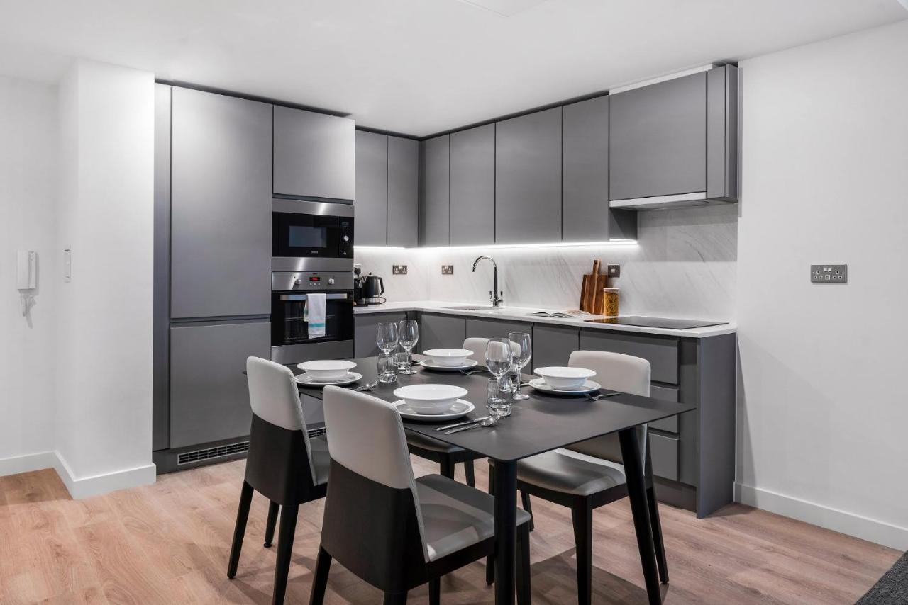 Citysuites 2 Aparthotel 맨체스터 외부 사진 The photo shows a modern kitchen and dining area. The kitchen features sleek, gray cabinetry and a countertop that complements the overall aesthetic. There are built-in appliances, including an oven and refrigerator, arranged neatly. Next to the kitc