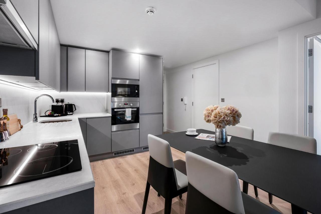 Citysuites 2 Aparthotel 맨체스터 외부 사진 The photo shows a modern kitchen and dining area. The kitchen features sleek gray cabinets, a countertop with an embedded cooktop, and built-in appliances, including an oven and microwave. There’s a small coffee maker on the counter. Adjacent to the 