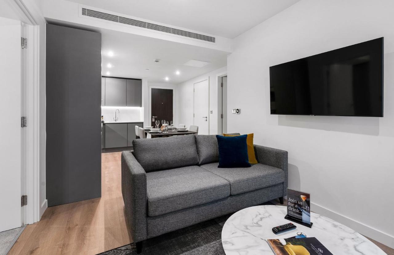 Citysuites 2 Aparthotel 맨체스터 외부 사진 The photo shows a modern living space that includes a gray sofa with colorful cushions, a round marble coffee table, and a flat-screen TV mounted on the wall. In the background, there is a kitchen area featuring sleek cabinets. The flooring is light 