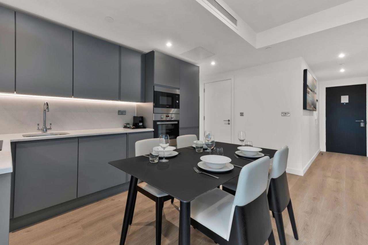 Citysuites 2 Aparthotel 맨체스터 외부 사진 The photo shows a modern kitchen and dining area. There are sleek gray cabinetry and countertops, with a built-in oven and microwave. The kitchen is well-lit, featuring under-cabinet lighting that adds to the contemporary feel. In the dining area, th